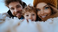 Happy young family with curly haired toddler smiling at camera in winter setting, close up portrait through snow covered foreground, warm emotional moment.