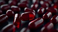 Red transparent capsules with liquid medicine on dark background, macro photography showing pharmaceutical pills in dramatic lighting for healthcare concept.