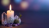 Mystical altar setup with burning candle, crystals, pentagram pendant and dried herbs for spiritual rituals, meditation and witchcraft practices.