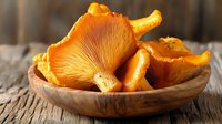 Fresh wild chanterelle mushrooms in wooden bowl on rustic table, bright orange color and natural texture, raw organic forest fungi for cooking.