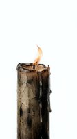 Old weathered candle with melted wax dripping down sides burning bright flame on white background isolated for design projects and creative concepts.