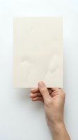 Hand holding blank cream textured paper sheet against white background for mockup design and presentation purposes.