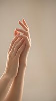 Elegant female hands with manicured nails in graceful pose against soft beige background for skincare and beauty concepts.