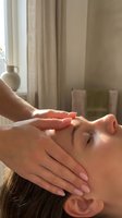Young Caucasian woman receiving a relaxing facial massage at a spa, eyes closed, warm natural light, promoting wellness and skincare treatments.