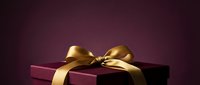 Luxury gift box with golden bow on dark purple background, perfect for holiday, celebration, and premium product packaging designs.