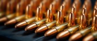 Rows of copper-tipped ammunition arranged in orderly formation, showcasing metallic sheen and precision manufacturing for hunting or sport shooting.