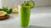 Fresh green smoothie with cucumber garnish and mint leaf in tall glass, healthy detox drink for wellness and nutrition.