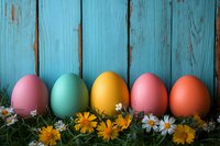 Colorful Easter eggs arranged in row with fresh spring daisies and yellow flowers against rustic turquoise wooden background. Festive holiday composition.