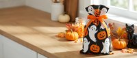 Halloween ghost decoration bag with pumpkins and autumn leaves on wooden kitchen counter for seasonal home decor and festive party atmosphere.