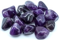 Polished purple amethyst stones arranged in group showing natural crystal formation and varying shades of violet color on white background for jewelry design.