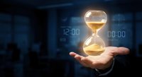 Businessman hand holding glowing hourglass with sand flowing in modern office environment representing time management and deadline concepts.