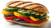 Grilled vegetable panini sandwich with zucchini, bell peppers and eggplant on crusty bread isolated on white background for healthy food designs.