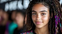 Young African American woman with colorful braids and bright smile against blurred background, radiating confidence and joy in casual modern style.