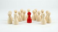 Red wooden pawn standing out among natural wood pawns on white background. Leadership, uniqueness, and team management concept for business presentations.