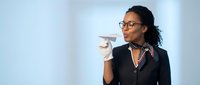 Professional African American businesswoman in glasses holding paper airplane in modern office setting with copy space for corporate concepts.