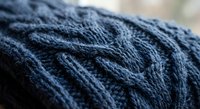 Navy blue cable knit sweater texture with intricate braided pattern detail for cozy winter fashion and textile design projects.