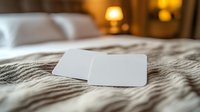 White blank cards on cozy bed with warm lighting, textured bedding creates intimate atmosphere for mockup presentation or romantic message.