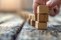 Hand stacking wooden blocks on textured surface, representing business growth, construction, development, and strategic planning.
