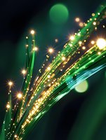 Glowing green fiber optic strands with golden light sparkles against dark background create magical technology atmosphere for communication concept designs.