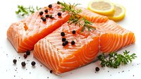 Fresh raw salmon fillets seasoned with black peppercorns, dill, and lemon slices on white background, close up view of pink fish meat texture and herbs.