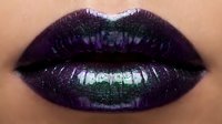Deep plum lipstick with iridescent shimmer and metallic green undertones creates a bold, glamorous makeup look for cosmetics and beauty campaigns.