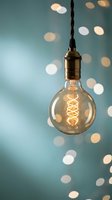 Vintage Edison bulb hanging on twisted cord with warm glowing filament against soft bokeh lights background for cozy interior design and lighting concepts.