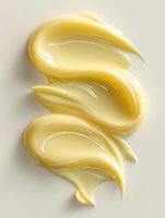 Creamy yellow cosmetic product smear texture isolated on beige background, showing glossy skincare or makeup consistency for beauty industry use.