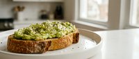 Fresh avocado toast with seeds and herbs on rustic bread served on white plate in bright modern kitchen for healthy breakfast or brunch meal.
