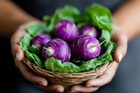 Fresh purple turnips with green leaves in woven basket held by female hands against dark background, selective focus on vegetables for food photography.