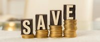 Wooden letter blocks spelling SAVE on stacks of golden coins showing financial growth and money saving concept for investment planning.
