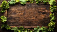 Fresh green lettuce leaves creating natural border frame on dark rustic wooden background, top view. Empty space for menu, recipe or healthy food concept.