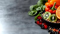 Fresh organic fruits and vegetables arranged on gray stone surface with kiwi, berries, citrus and leafy greens for healthy eating and nutrition content.