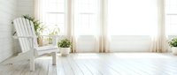 Bright minimalist interior with white Adirondack chair, potted plants, and large windows casting natural light on wooden floor for home decor and design projects.