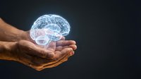 Male hand holding glowing holographic brain illustration against dark background, representing neuroscience, artificial intelligence, mental health, innovation and technology concepts.
