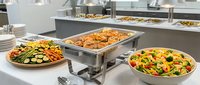 Professional catering buffet setup with chafing dishes, fresh salads and hot food platters in modern commercial kitchen for events and hospitality service.