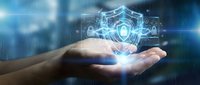 Businessperson holding glowing digital security shield with holographic interface, representing cybersecurity, data protection, and technology innovation for business solutions.