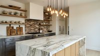 Modern kitchen interior with marble waterfall island, pendant lighting and brick backsplash for contemporary home design and renovation projects.