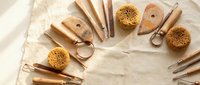 Natural wooden massage tools and sea sponges arranged on linen fabric for spa wellness treatments and body care routines.