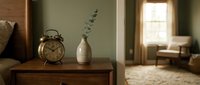 Vintage brass alarm clock and dried eucalyptus in ceramic vase on wooden nightstand with warm sunlight, suitable for home decor and interior design projects.