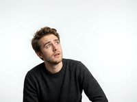 Young adult male with light brown hair and Caucasian ethnicity wearing dark charcoal sweater, looking upward thoughtfully against white background. Suitable for business, lifestyle, and motivational content.