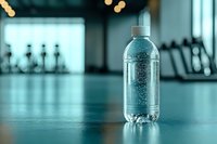 Clear plastic water bottle with condensation droplets on turquoise gym background, fitness equipment silhouettes visible. Fresh hydration concept for sports.