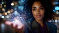 Young African American businesswoman with natural curly hair holding magical glowing light particles against blurred city bokeh background at night. Professional portrait.