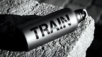 Metallic sports water bottle with train text label lying on sandy surface in monochrome lighting for fitness and hydration concepts.