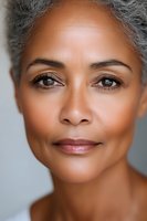 Close up portrait of mature African American woman with natural gray hair and gentle smile showing confidence and wisdom against light background.