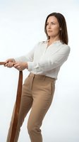 Professional businesswoman in white shirt and beige trousers leaning on wooden cane, confident pose isolated on white background for corporate design.