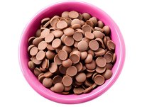Milk chocolate baking chips in bright pink ceramic bowl against white background, top view angle for cooking and confectionery projects.