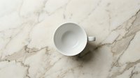 White ceramic mug on marble surface, overhead view. Isolated cup on stone background for product mockup, branding, and tableware design projects.