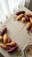 Fresh colorful sweet potatoes and carrots arranged on rustic wooden cutting board with bay leaves for healthy cooking and meal preparation.