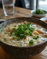Creamy chicken noodle soup garnished with fresh chopped green onions in rustic ceramic bowl. Homestyle comfort food with tender shredded meat and pasta in savory broth.