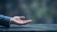 Open palm of a Caucasian male hand resting on wooden surface against blurred outdoor background, conveying concepts of offering, receiving, or empty gesture for business and motivational content.